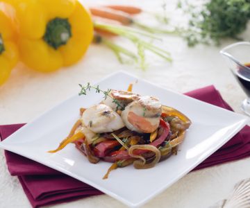 Sint-jakobsschelpen op een bedje van gekarameliseerde uien met wortelen en paprika's in sojasaus