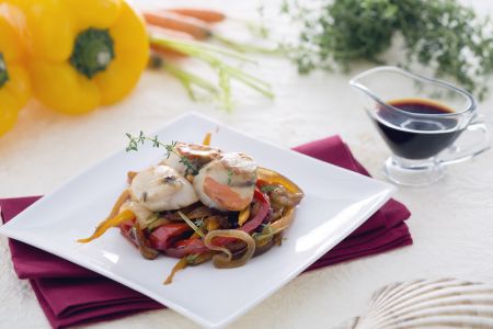 Sint-jakobsschelpen op een bedje van gekarameliseerde uien met wortelen en paprika's in sojasaus