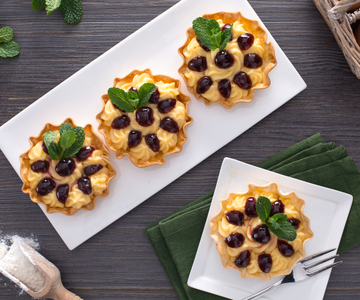 Kleine taartjes gevuld met banketbakkersroom en zure kersen