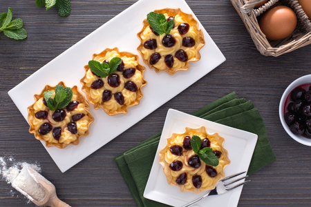 Kleine taartjes gevuld met banketbakkersroom en zure kersen