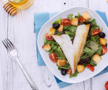 Gerookte dorade op een gemengde salade met croutons en honingvinaigrette