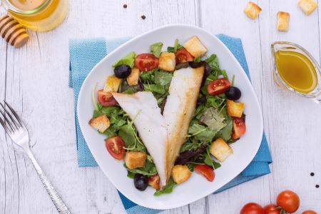 Gerookte dorade op een gemengde salade met croutons en honingvinaigrette