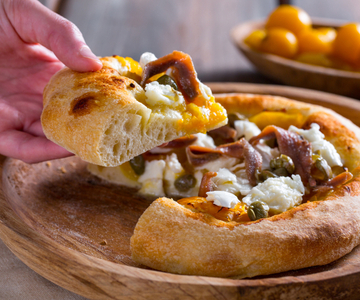 Pizza met gele cherrytomaatjes, ansjovis en kappertjes