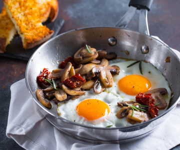 Gebakken eieren met paddenstoelen en zongedroogde tomaten
