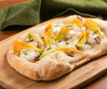 Pinsa met courgettebloemen, ansjovis en kaascrème