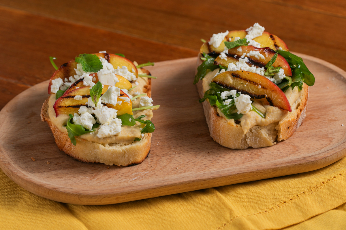 Crostone met hummus, gegrilde perziken, feta en rucola