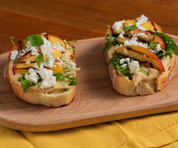 Crostone met hummus, gegrilde perziken, feta en rucola